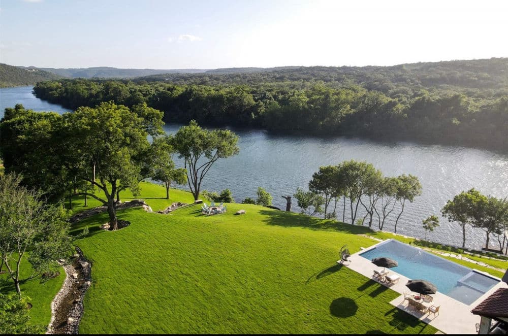 Scenic river view with pool and lush green lawn, ideal for relaxation and outdoor activities.
