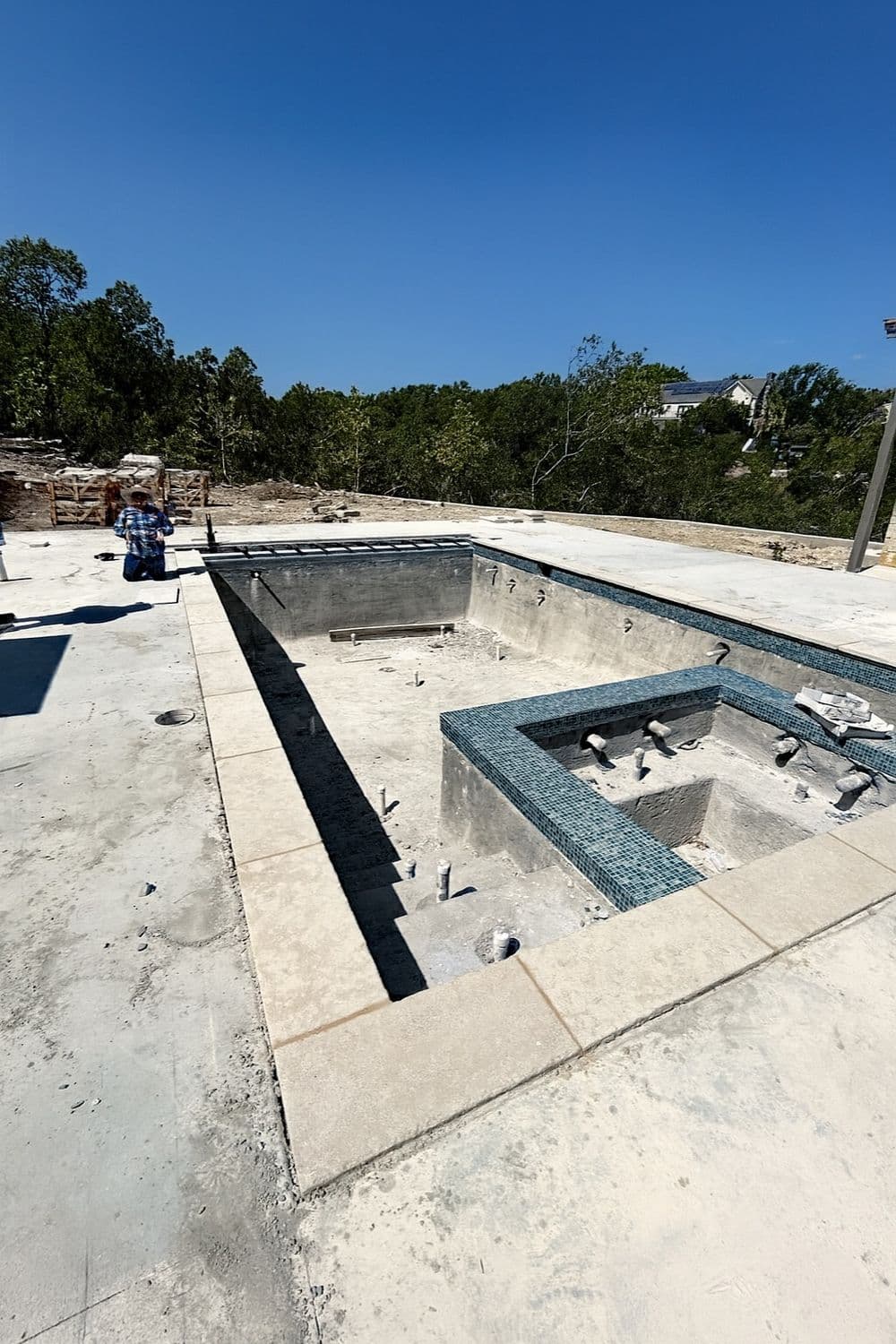 Construction site of a luxury swimming pool with spa and surrounding deck area.