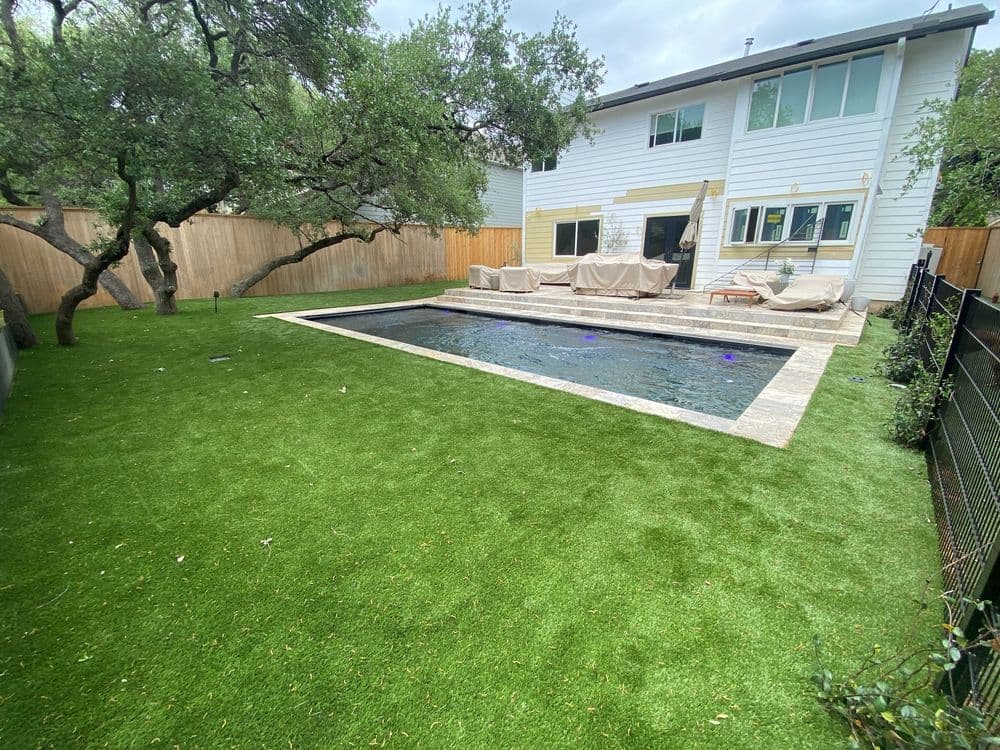 Modern backyard with a pool, artificial grass, and comfortable seating area.