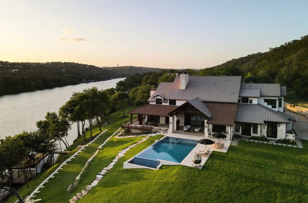 Modern waterfront villa with pool and landscaped yard beside a serene river.