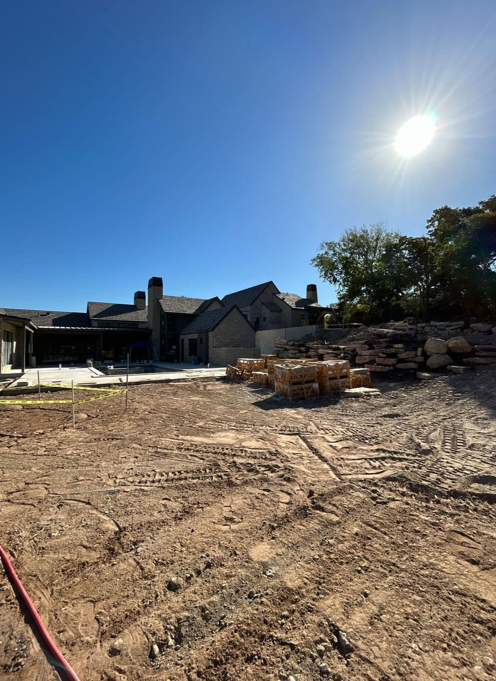 Newly constructed home in a clear sky, with construction materials piled nearby and sun shining.