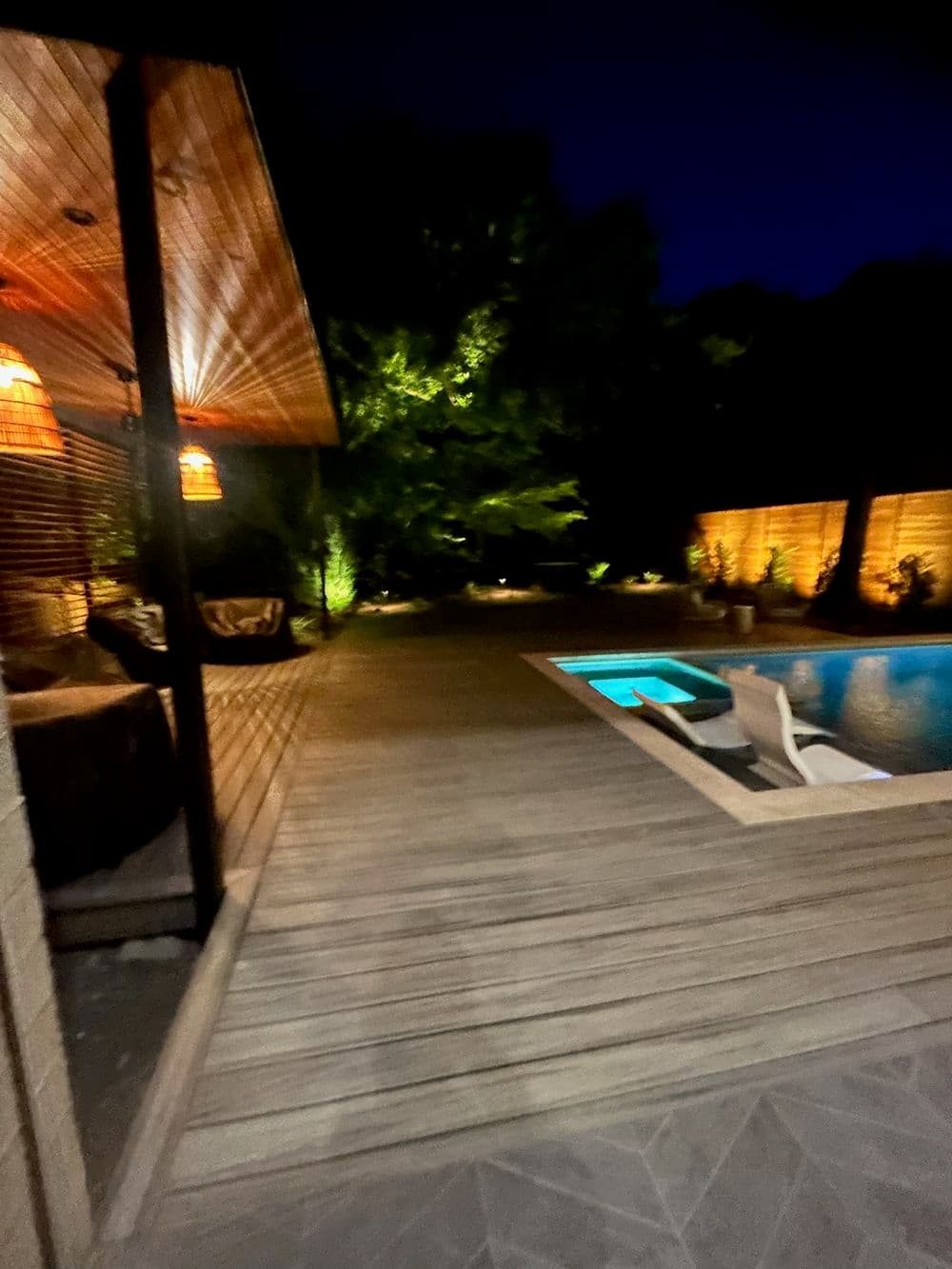 Stylish outdoor terrace at night with illuminated pool and cozy lounge area.