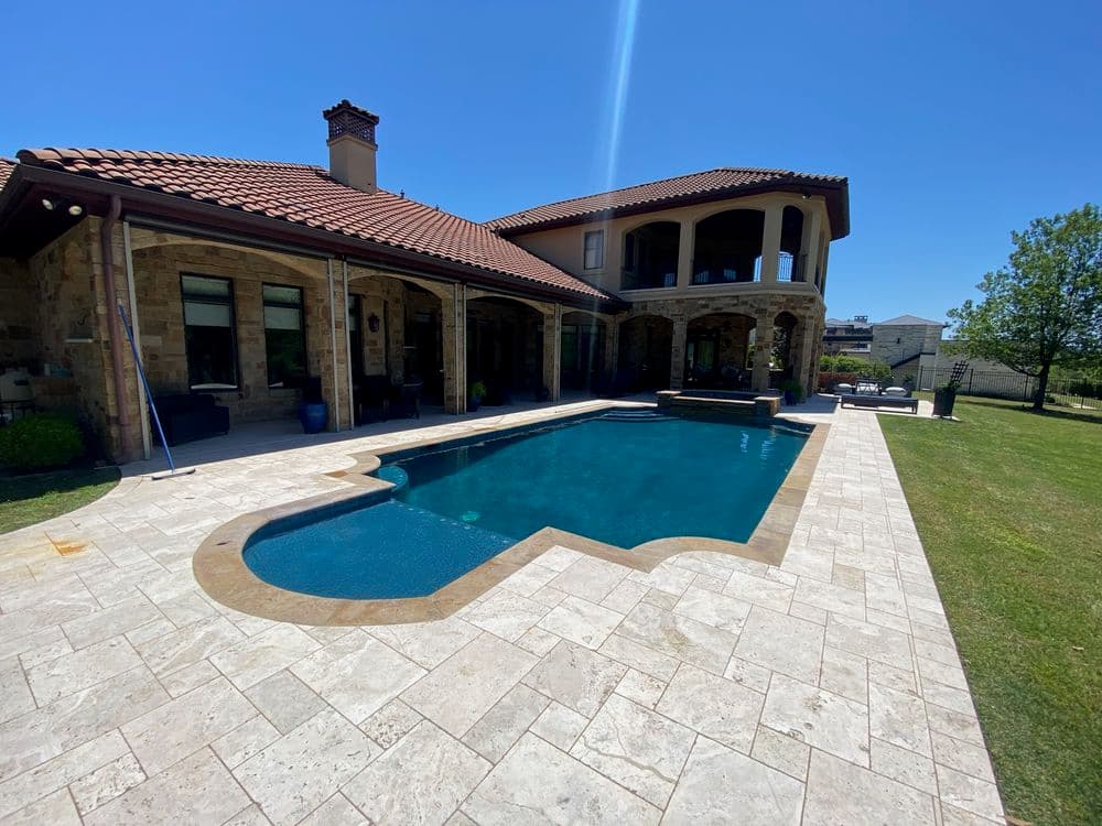Luxury home with a swimming pool and outdoor patio under a clear blue sky.