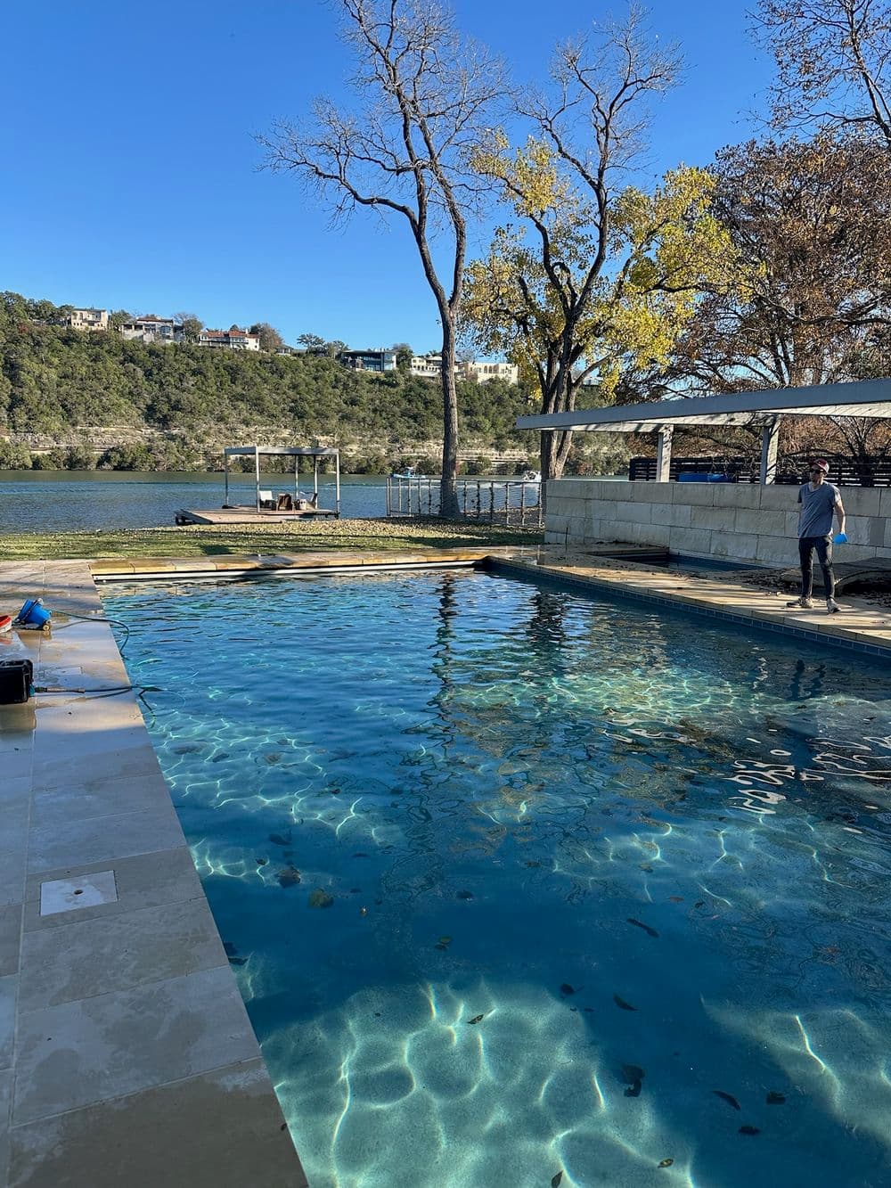 Luxury poolside view overlooking a serene lake with autumn trees and sunny skies.
